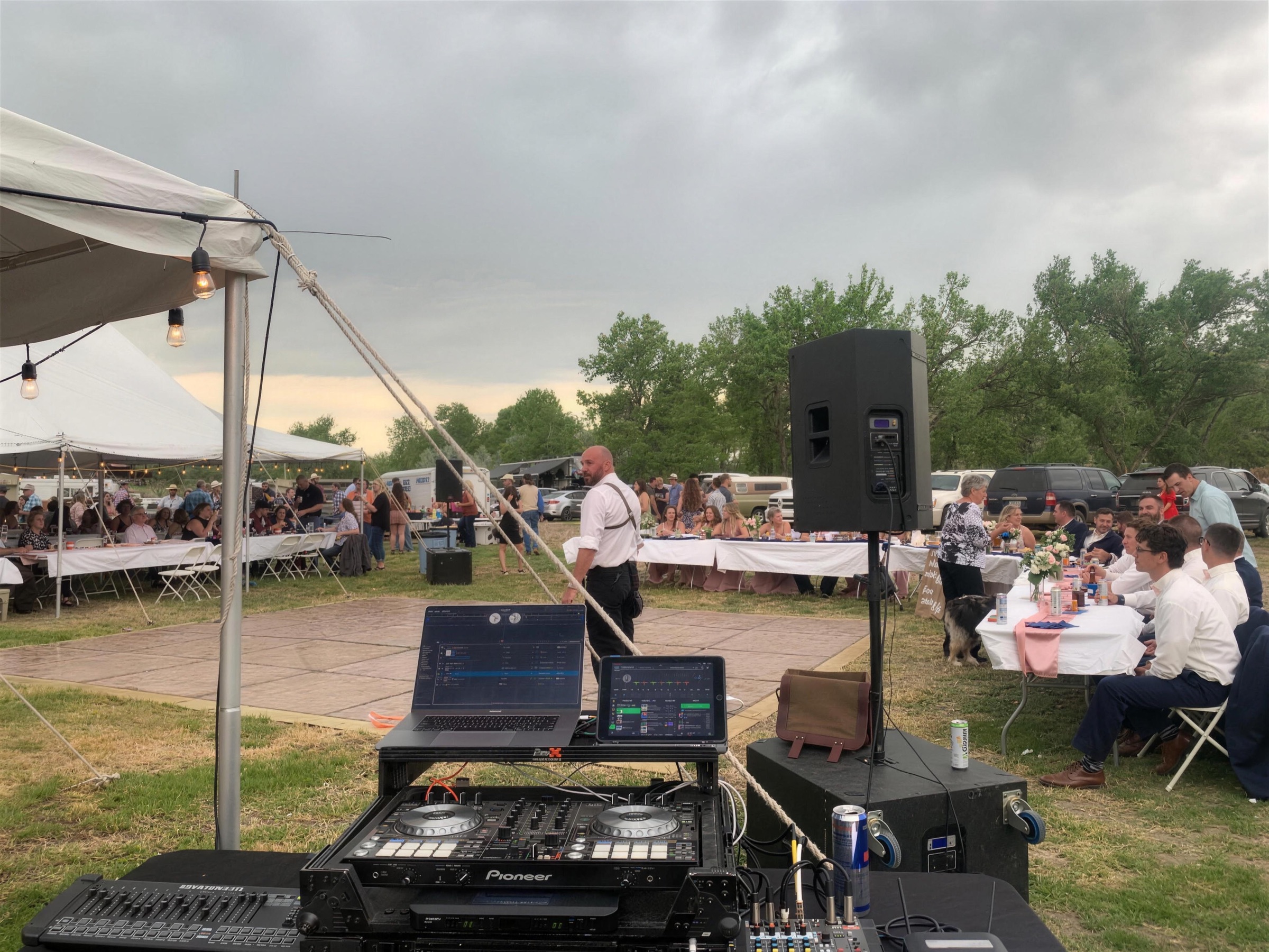 DJ booth under an open tent with guests seated at outdoor tables