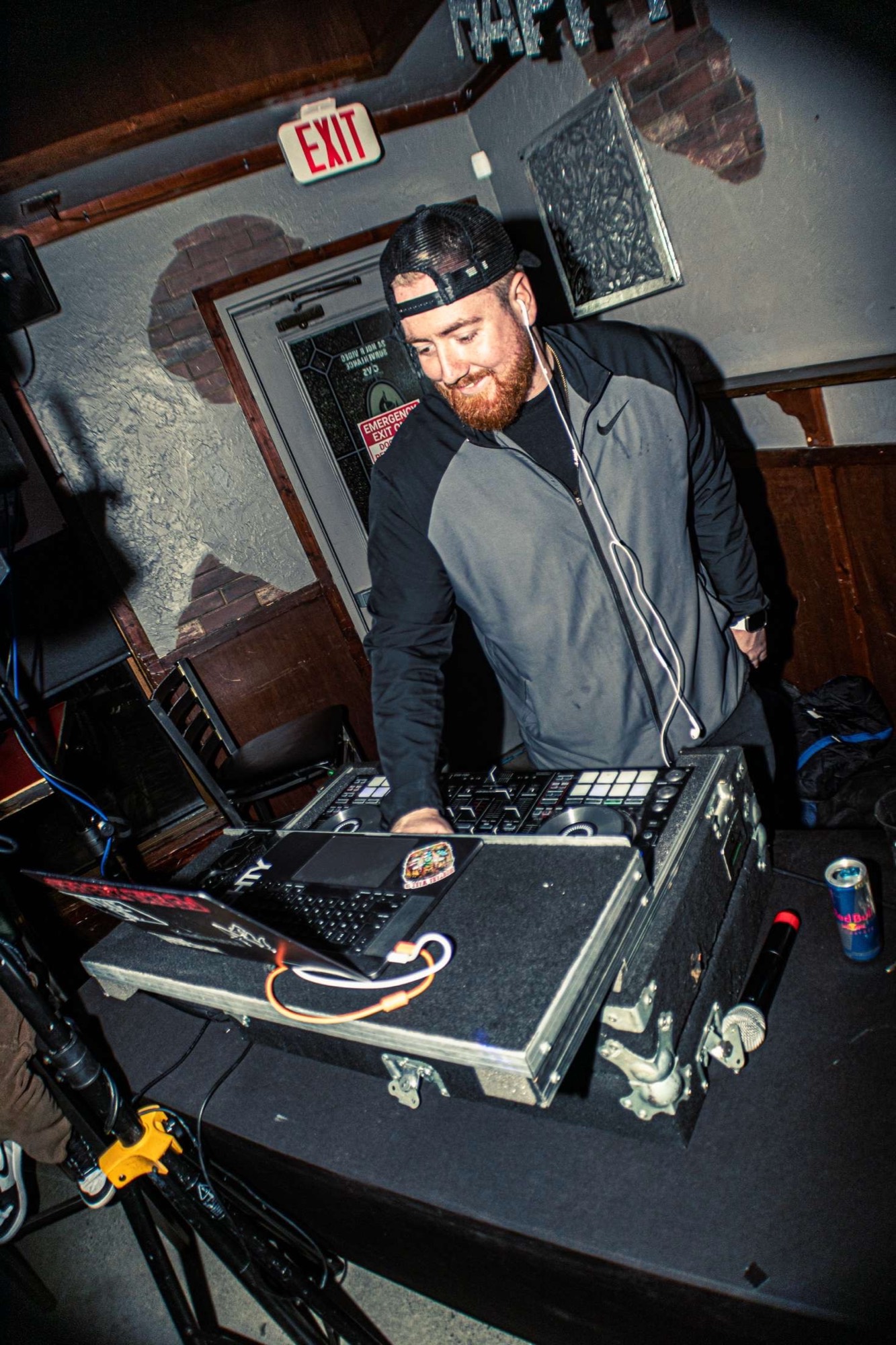 DJ in a cap working the decks in a dimly lit room